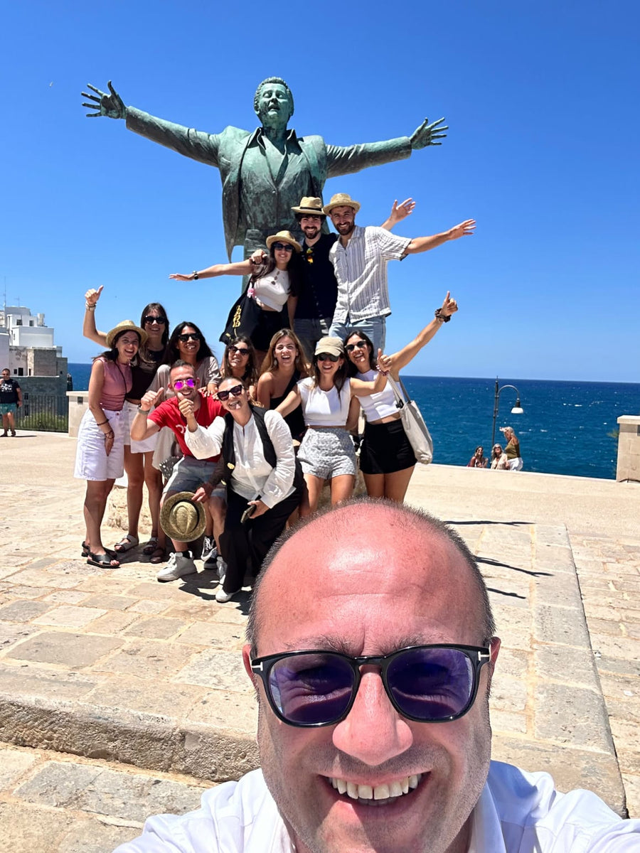 Lorenzo Cappiello with travellers near the statue of Domenico Modugno in Polignano a Mare