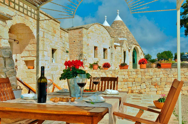 Wine glasses and a table set among the trulli